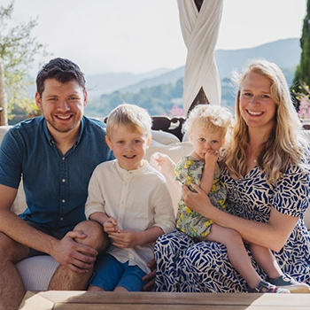 Smiling young family at rural family hotel with panoramic mountain view